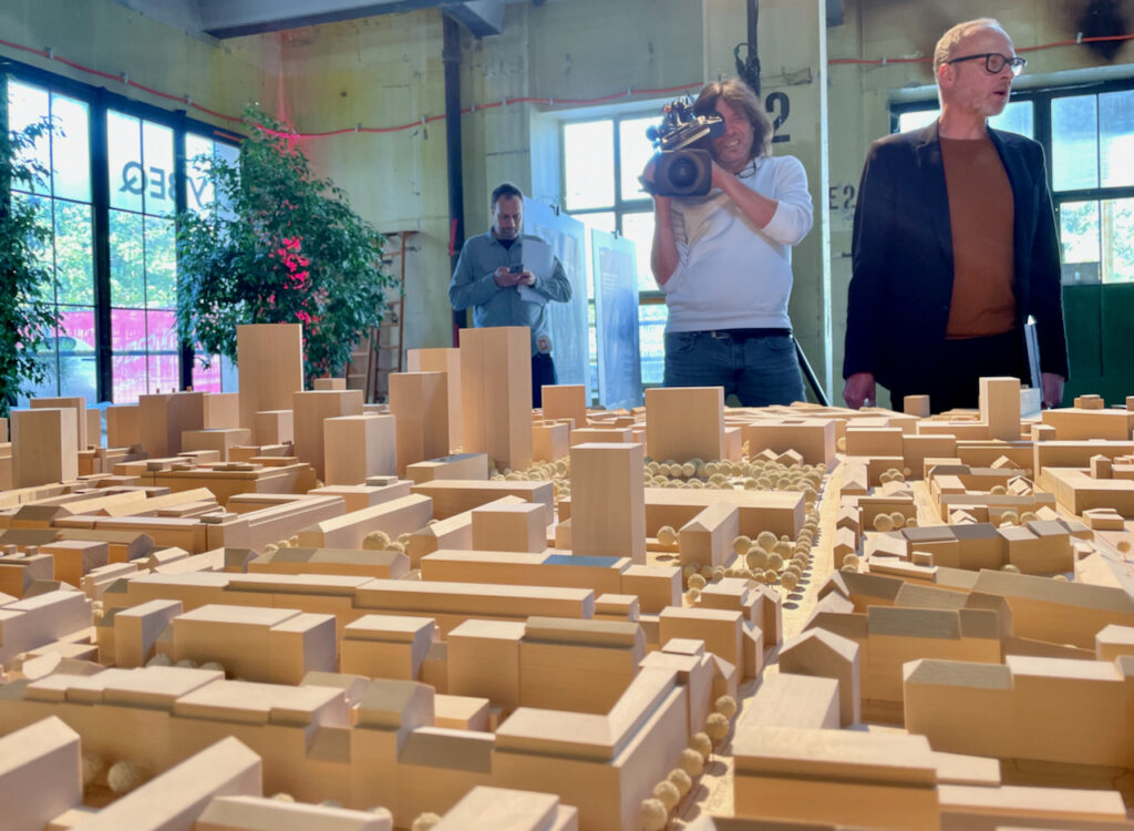 Blick auf einen Ausschnitt des Stadtmodells von Basel mit KantonsbaumeisterBeat Aeberhard und einem Kameramnn von Telebasel im Hintergrund.   
